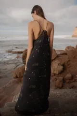 Vestido largo negro de seda con breteles finos y escote en V con puntilla. Estampado con motivos astrológicos dorados.
