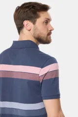 Remera polo de piqué con rayas horizontales en tonos beige, verde y azul. Tiene cuello y mangas en color azul oscuro, cierre con dos botones y logo bordado en el pecho.
