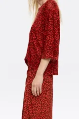 Jersey de lino color rojo con estampado animal print en marrón oscuro, corte recto, escote redondo, manga 3/4 con puño estrecho y sisa cuadrada con fruncido en el hombro.