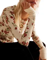 Blusa térmica color crema con estampado floral en tonos rojos y verdes, de mangas largas con puños acampanados.