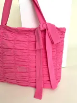 Bolso tipo tote color fucsia, 100% algodón, con diseño drapeado, moña fija y grifa de acrílico Cilento.