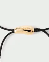Gargantilla con cordón negro y dije dorado en forma de lágrima.