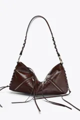 Bolso de hombro marrón de cuero sintético con dos bolsillos frontales con cremallera y tiras decorativas. El asa es trenzada y tiene herrajes metálicos.