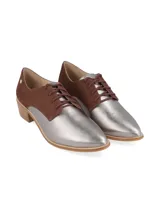 Zapato acordonado de cuero color plateado con puntera fina y detalle de cuero marrón en el talón.