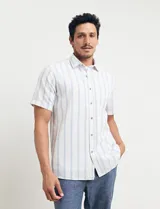 Camisa de manga corta a rayas verticales celestes y blancas, con cuello clásico y botones marrones.