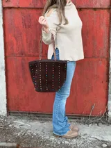 Cartera tipo tote bag de cuero color marrón chocolate, con apliques de cuentas de colores y asas trenzadas.