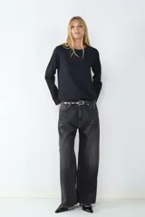 Jean de tiro alto color negro, corte loose con pernera ancha. Diseño clásico de cinco bolsillos con cierre de cremallera y botón metálico.