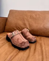 Zueco negro liviano con suela de goma y detalles metálicos, de diseño moderno.