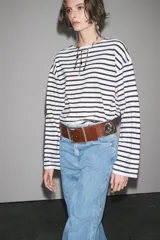 Camiseta de manga larga a rayas horizontales blancas y negras, con cuello redondo y bajo con aberturas laterales.