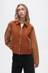 Chaqueta corta color marrón con detalles en color camel, de gamuza sintética, con cuello camisero, cierre frontal con cremallera y apliques de tachas plateadas.