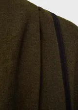 Poncho verde militar con ribete negro en contraste, cuello alto y diseño holgado. Incluye cinturón negro con hebilla dorada.