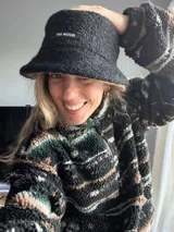 Gorro tipo bucket negro con textura de lana rizada y etiqueta con la inscripción "The Mood". Interior color marrón.