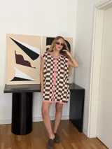 Vestido corto tejido en jacquard de algodón a cuadros marrones y beige, con terminaciones en color rosa. Tiene cuello redondo, botones frontales y corte sin mangas.