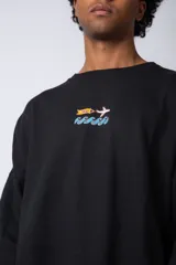 Buzo negro de corte oversize con cuello redondo y estampa de un avión sobre olas.