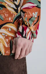 Camisa de manga larga con estampado de flores y hojas en tonos naranja, blanco, rojo, verde y negro.