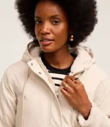 Campera parka color beige, forrada con peluche sintético, confeccionada en poliuretano. Tiene capucha, ajuste en el cuello, cierre delantero, bolsillos delanteros con solapa y textura gomosa.