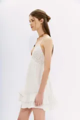Vestido corto blanco de algodón con breteles finos, escote en V con detalle de bordado calado, espalda baja con elástico y volados en el ruedo.