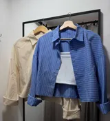 Camisa celeste con rayas verticales blancas, de manga larga con puños abotonados y corte holgado.