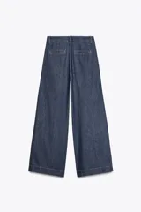 Pantalón de jean azul oscuro, corte wide leg, tiro alto con pinzas delanteras, bolsillos laterales y cierre frontal con cremallera y botón.