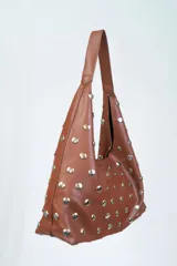 Cartera tipo hobo de cuero color marrón con apliques de tachas plateadas.