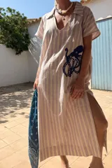 Túnica de lino a rayas verticales color lila y blanco, con cuello polo y bordado de un pulpo azul en el frente.