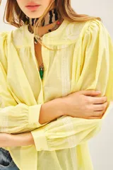 Camisa amarilla de voile con bordados en el frente y las mangas, de corte amplio, con cuello redondo y cierre frontal con botones.