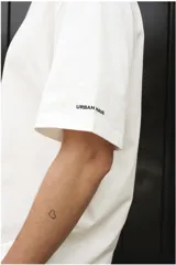 Remera blanca de algodón con estampado en la espalda con la frase "Follow the Waves" y dibujos de conchas marinas en color celeste.