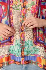 Camisa de mangas largas con cuello clásico y cierre frontal con botones. Estampado multicolor con motivos florales y geométricos.