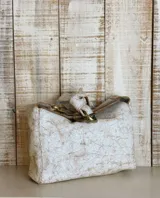 Cartera tipo bolso de mano color beige con textura símil piel de cocodrilo. Tiene correa corta de hombro con eslabones dorados.