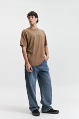 Remera marrón de manga corta con cuello redondo y estampado en la espalda con motivos geométricos y el logo de la marca Mistral.