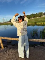 Campera de jean color manteca con apliques de flores de crochet en tonos neutros, corte recto y cierre con botones.