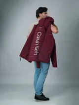 Campera acolchada Calvin Klein color bordó con capucha y cierre frontal con cremallera. Tiene bolsillos laterales con cremallera y logo de la marca en el pecho y en la manga.