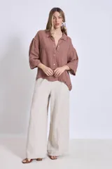 Camisa de lino color terracota, con cuello camisero, botones frontales y mangas amplias de tres cuartos.