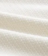 Remera de mangas cortas color crema, confeccionada con 50% algodón y 50% poliéster, con cuello redondo y tejido texturizado.