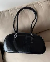 Cartera baguette negra de cuero sintético con doble asa corta y cierre superior con cremallera.