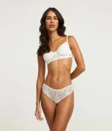 Bombacha de lencería femenina color blanco, modelo bikini hilo, confeccionada en encaje floral. Presenta un diseño cavado en la parte trasera y detalles de encaje en los bordes.