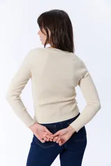 Remera de manga larga color crudo, con escote en V amplio y tejido acanalado.