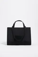 Bolso shopper de nylon negro, estructura blanda, con doble asa de mano y cierre principal de cremallera. Presenta una etiqueta logotipada en el frente y herrajes metálicos lacados.