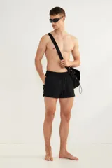 Short de baño negro de sirsaca con aberturas laterales cortas, cintura elástica con cordón ajustable, bolsillos laterales y bolsillo trasero con cierre autoadherente. Tiene suspensor interior de malla.