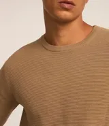 Suéter de punto color gris, con cuello redondo, manga larga y textura maquinetada.