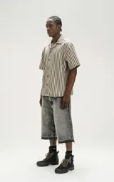 Bermuda denim larga color gris con efecto lavado, calce oversize, cintura con cinturón de ajuste y ruedo desflecado.