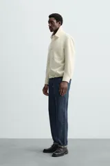 Sobrecamisa color crudo de corte regular fit, confeccionada en tejido con mezcla de viscosa. Tiene cuello solapa, manga larga con puños abotonados, bolsillo de parche en el pecho, bajo ajustable con cordones y cierre frontal con botones.