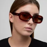 Lentes de sol con armazón grueso de policarbonato en tono bordó translúcido y diseño 3D redondeado. Poseen cristales polarizados de color marrón con protección UV400.