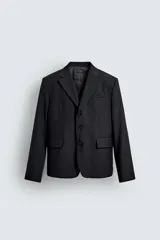 Blazer negro de corte relaxed fit confeccionada en tejido con lana. Cuello con solapas de muesca y manga larga acabada en puño con botones. Bolsillos de vivo en pecho y de solapa en cadera. Detalle de bolsillo interior. Bajo con aberturas en espalda. Cierre frontal de botonadura.