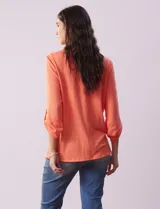 Blusa blanca de poliéster y rayón con escote en V bordado y mangas tres cuartos regulables con presilla y botón.