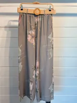 Pantalón palazzo verde claro con estampado de flores rosas, cintura elástica y lazo ajustable.