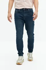Jean slim azul oscuro, tiro medio, con pasacintos y confeccionado en 98% algodón y 2% spandex.