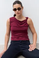 Top sin mangas color bordó con escote drapeado tipo cascada, ajustado al cuerpo.