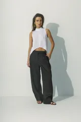 Top sin mangas blanco con cuello alto y bajo asimétrico, de textura arrugada.