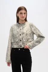 Chaqueta corta de algodón con estampado animal print en tonos grisáceos, cuello redondo, cierre frontal con botones a presión, bolsillos de parche en el pecho y corte recto.